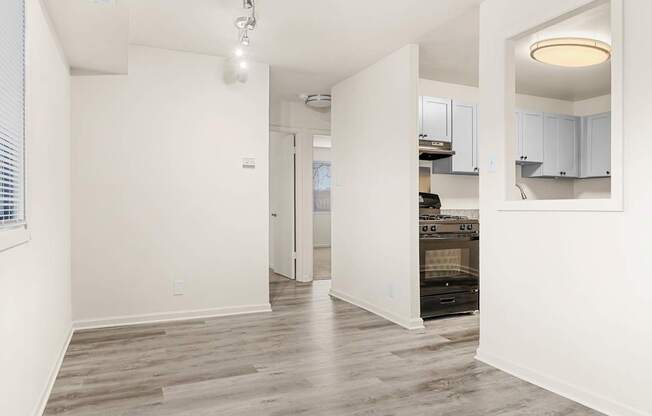 A spacious kitchen with white cabinets and a wooden floor.