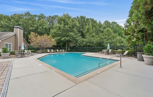 A swimming pool surrounded by trees and a house.