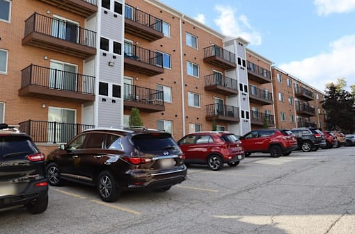 a parking lot full of cars in front of an apartment building