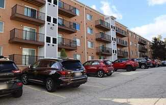 a parking lot full of cars in front of an apartment building