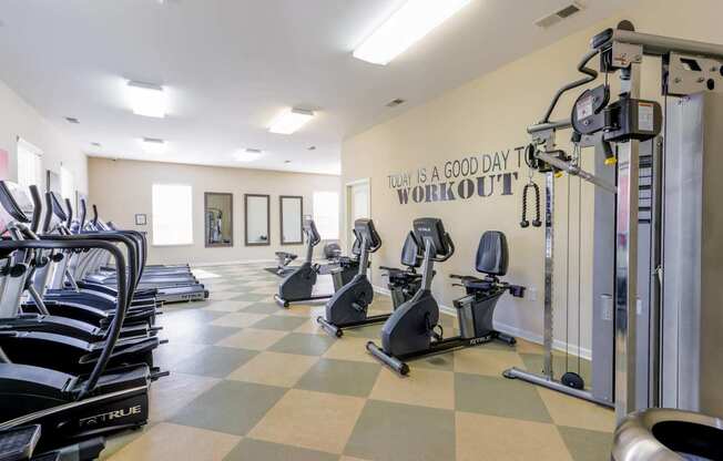 A gym with treadmills, exercise bikes and a wall that says "Today is a good day to workout".