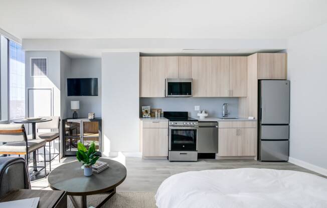 a bedroom with a bed and a kitchen with a refrigerator