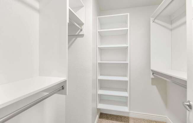 a closet in a white room with shelves and