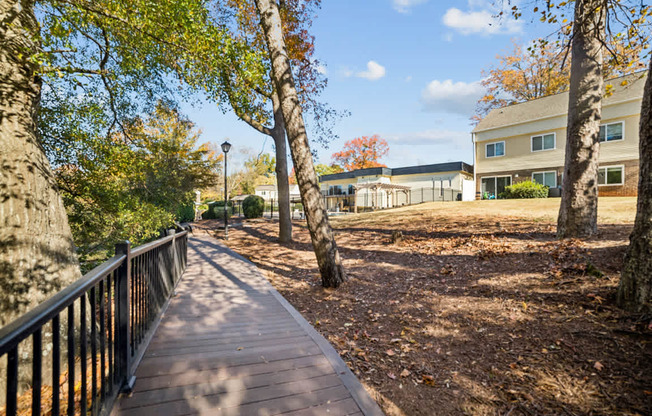 A wooden walkway with a metal railing is surrounded by trees.