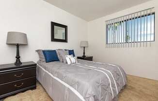 A bedroom with a bed, two lamps, and a picture on the wall.