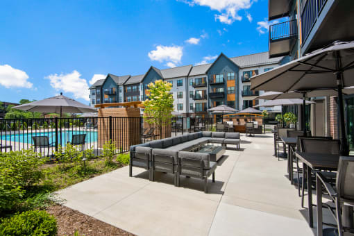 a patio with chairs and umbrellas next to a swimming pool