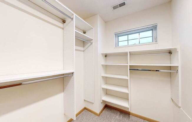A white closet with shelves and a window.