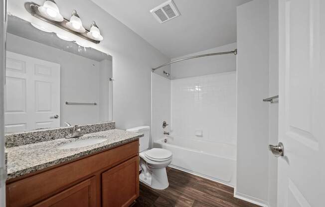 Upgraded bathroom with curved shower rod at Woodland Villa Apartments in Westland, MI.
