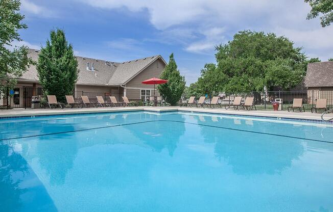 A sparkling outdoor swimming pool with landscaping and lounge chairs.