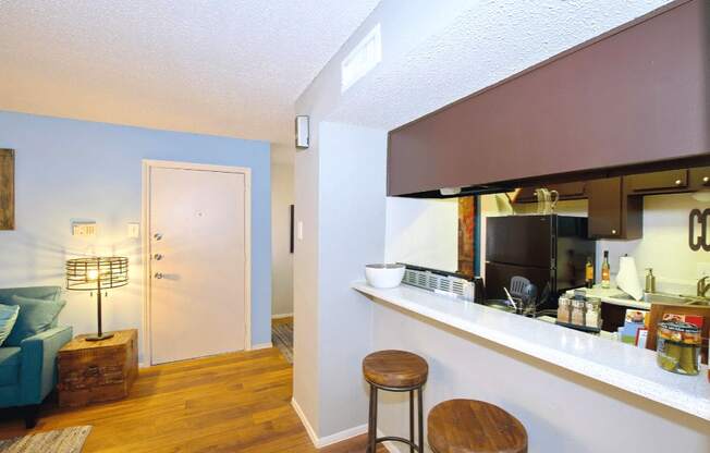 A kitchen area with a bar stool and a counter with a coffee maker.