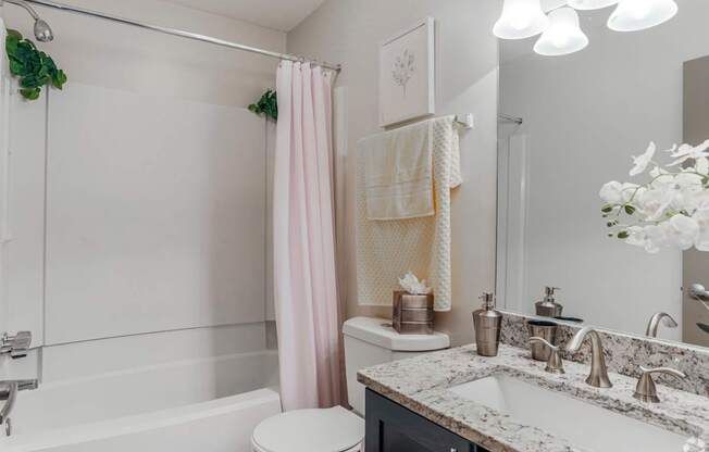 A white bathroom with a pink shower curtain.