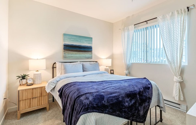 a bedroom with a bed and a window with white curtains