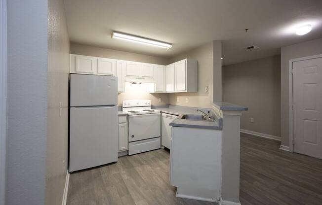 an empty kitchen with white appliances and white cabinets at Magnolia Pointe Apartments in Duluth, GA