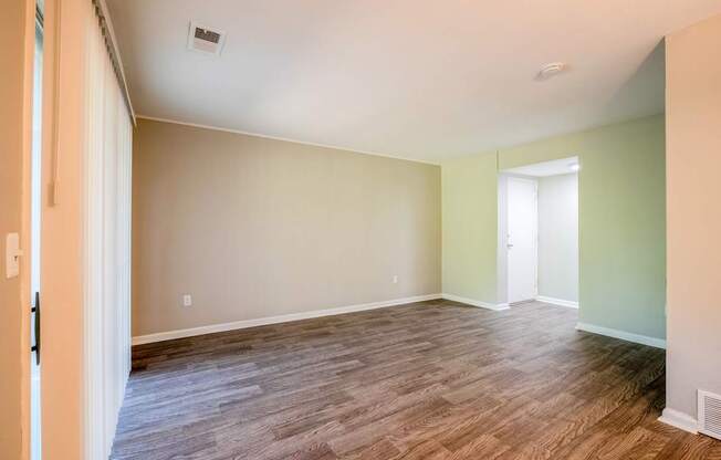 A room with wood flooring and a door on the right.
