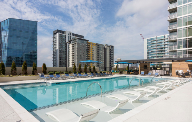 Outdoor pool deck with a lounge chairs and a skyline view.