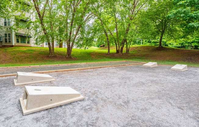 an empty parking lot with trees and a house in the background