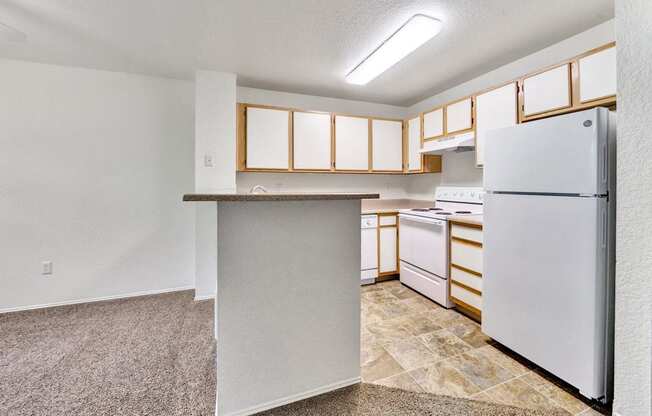 an empty kitchen with white appliances and white cabinets