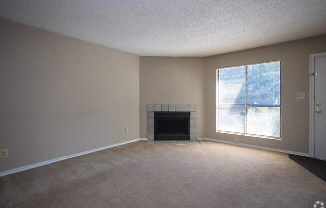 an empty living room with a fireplace and a window