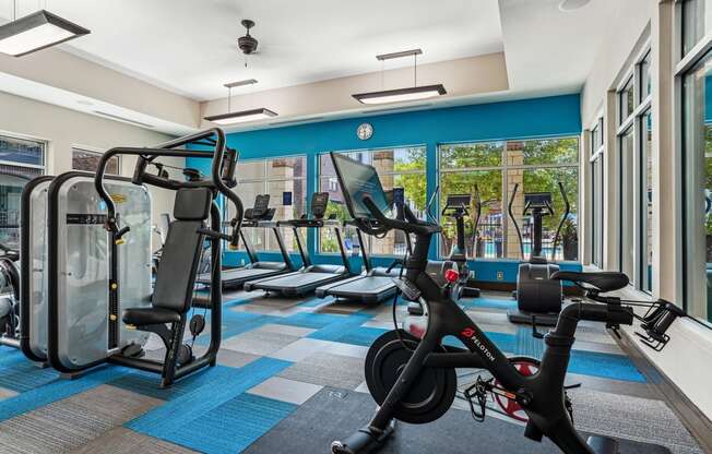 a gym with cardio machines and weights in a building with windows