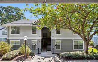 A grey house with a tree in front.