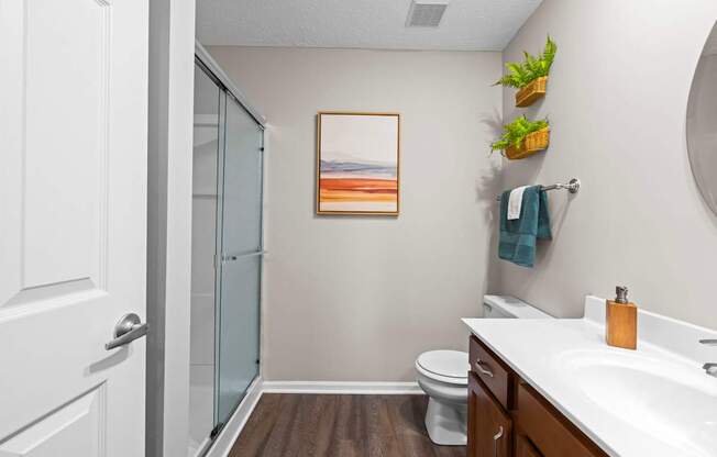 A bathroom with a toilet, sink, and a painting on the wall.