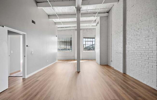 A long, empty room with white walls and wooden floors.