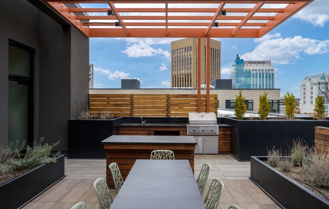a patio with a dining table and a city skyline in the background at The Lucy Boise Apartments, Boise, ID