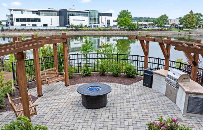 a patio with a fire pit and a lake with buildings in the background