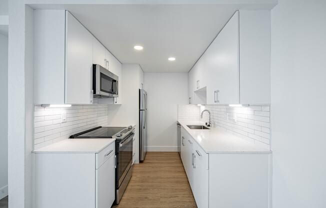 a kitchen with white cabinets and a stove and a refrigerator at Avenue Two Apartments, California