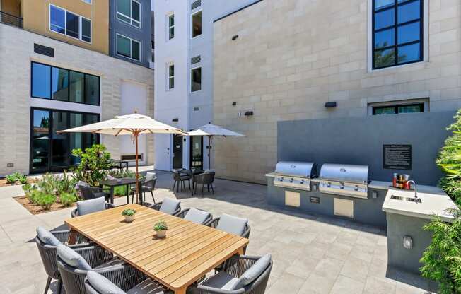 Patio with a wood table and chairs and a grill with two bbq grills at Array La Mesa, California