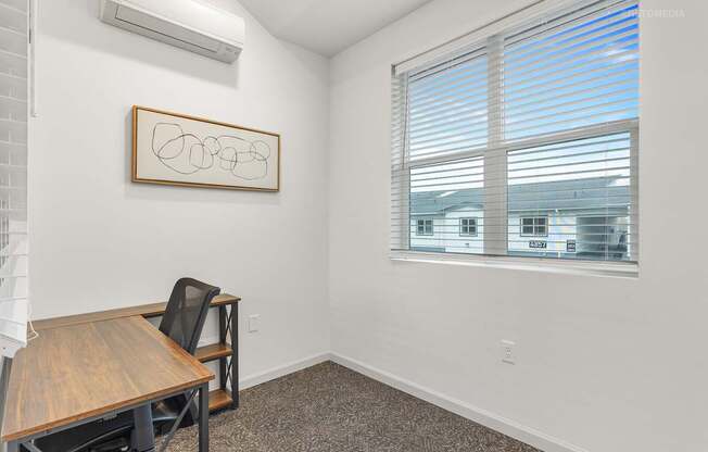 A room with a table and a window with blinds.