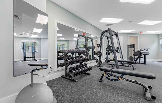 A gym with a mirror, weights, and exercise equipment.