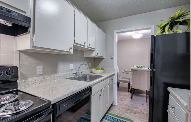A kitchen with white cabinets and a black refrigerator.