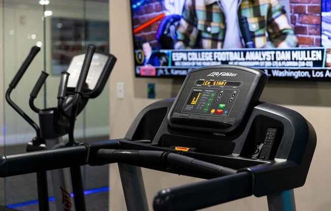 a treadmill in a gym with a tv in the background