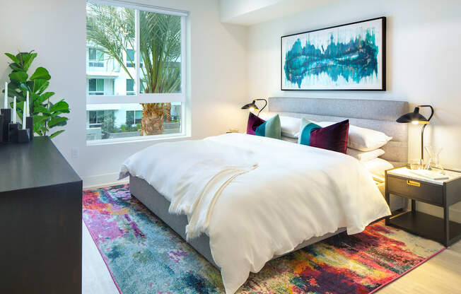 a bedroom with a bed and a rug in front of a window