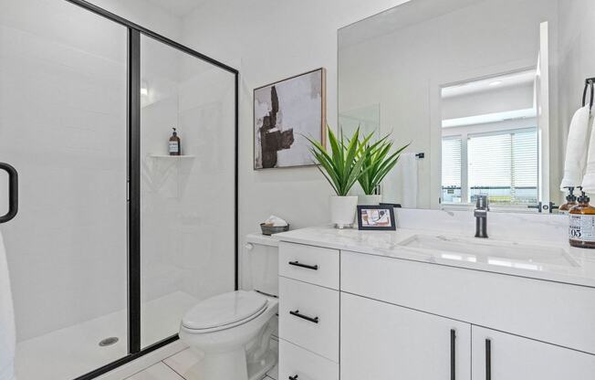 a white bathroom with a shower, a toilet, and a sink