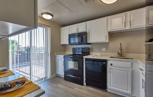 A modern kitchen with black appliances and white cabinets.