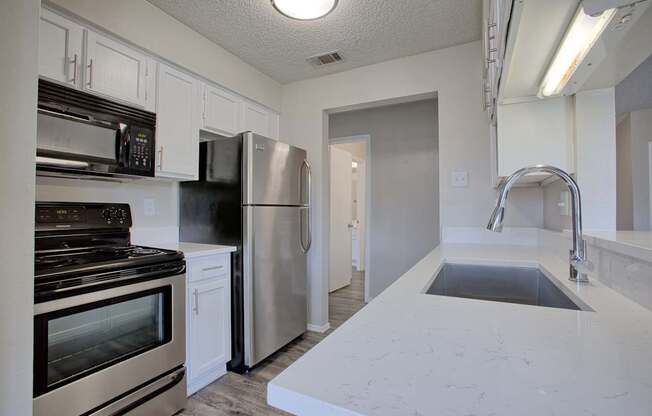 A kitchen with stainless steel appliances and white cabinets.