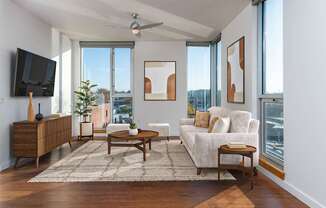 A living room with a white couch, a wooden coffee table, and a flat screen TV mounted on the wall.