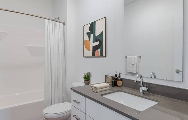 A bathroom with a white toilet, a sink, and a shower with a white curtain.