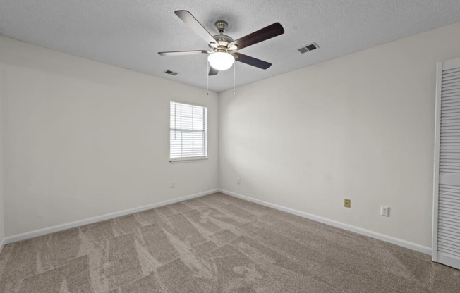 the living room is empty and has a ceiling fan