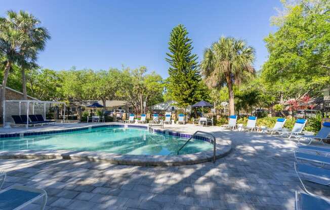 a pool with lounge chairs and trees in the background