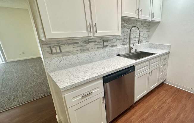 a kitchen with white cabinets and a stainless steel dishwasher