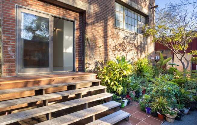 the front of a brick house with a large wooden porch and potted plants