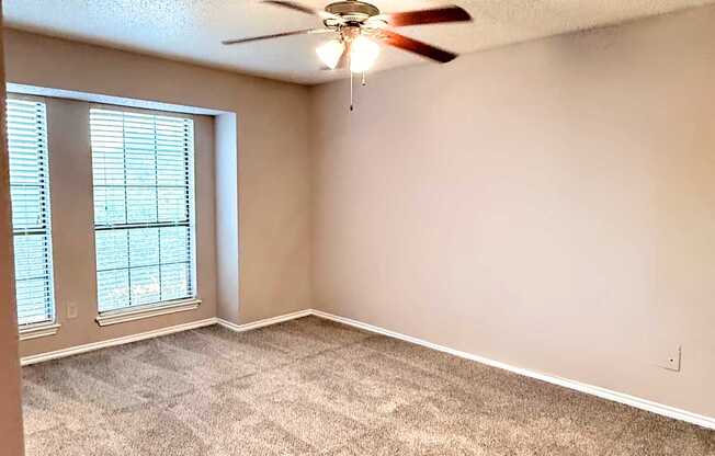 A room with a ceiling fan and carpeted floor.