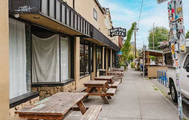A Baby Doll Pizza restaurant has wooden picnic tables outside.