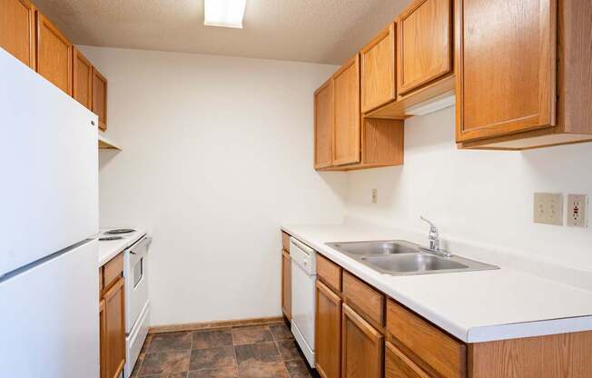 A kitchen with brown cabinets and a white fridge.