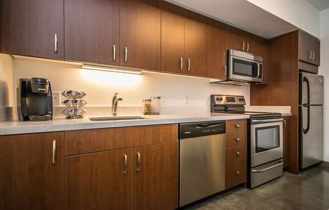 Portland Apartments - Corbett Heights - Chef-Inspired Kitchen with Wood-Style Cabinetry, Polished Concrete Flooring, Quartz Countertops, and Stainless Steel Appliances