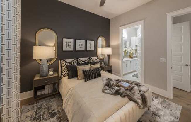 A bedroom with a bed, two lamps, and a mirror on the wall.