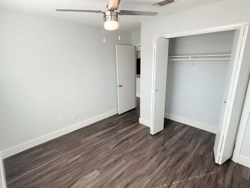 an empty bedroom with a closet and a ceiling fan